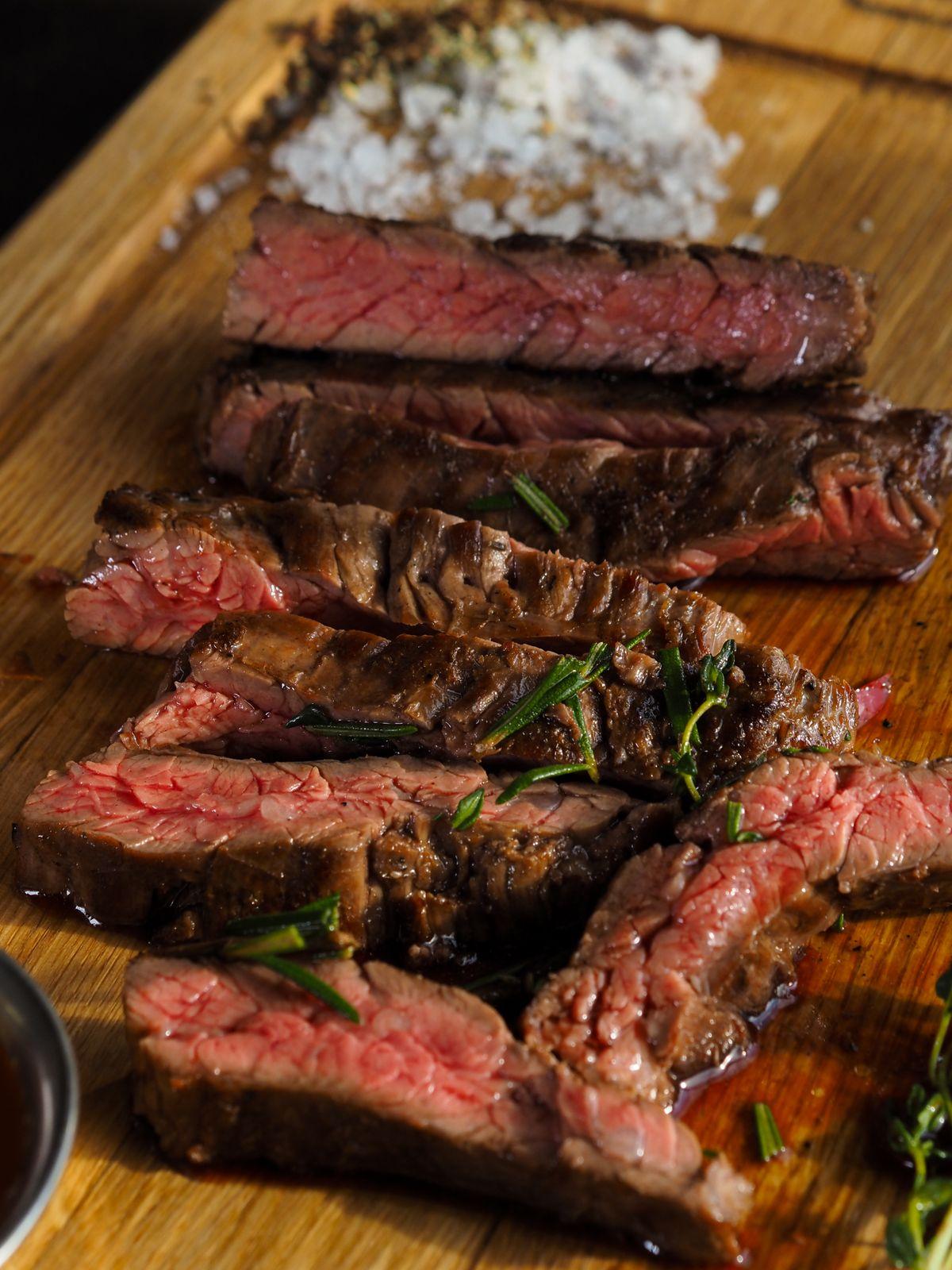 Sliced medium-rare steak resting on a wooden board